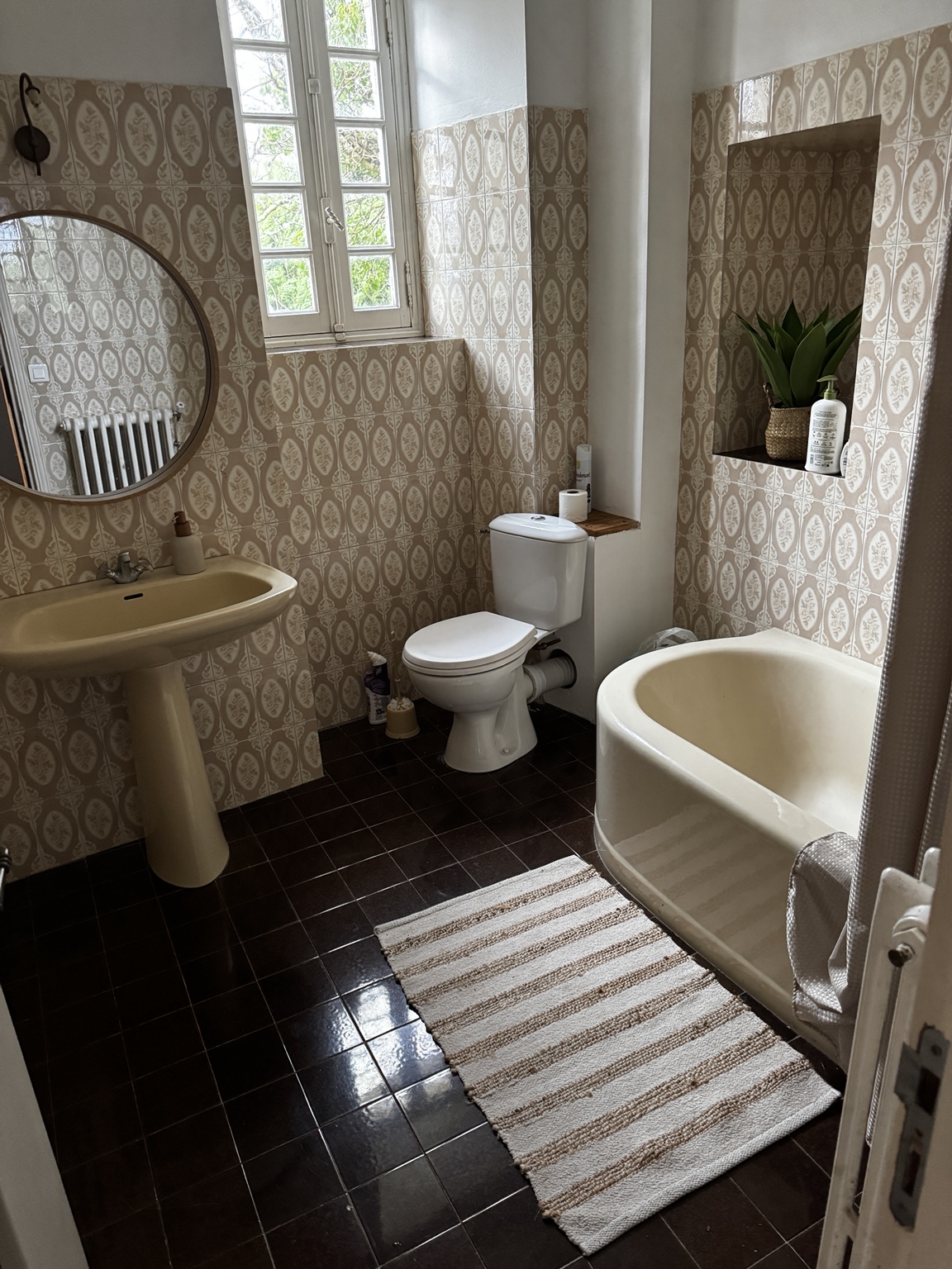 A bathroom at Maison Rivers with a roll-top bath, patterned walls and traditional fittings