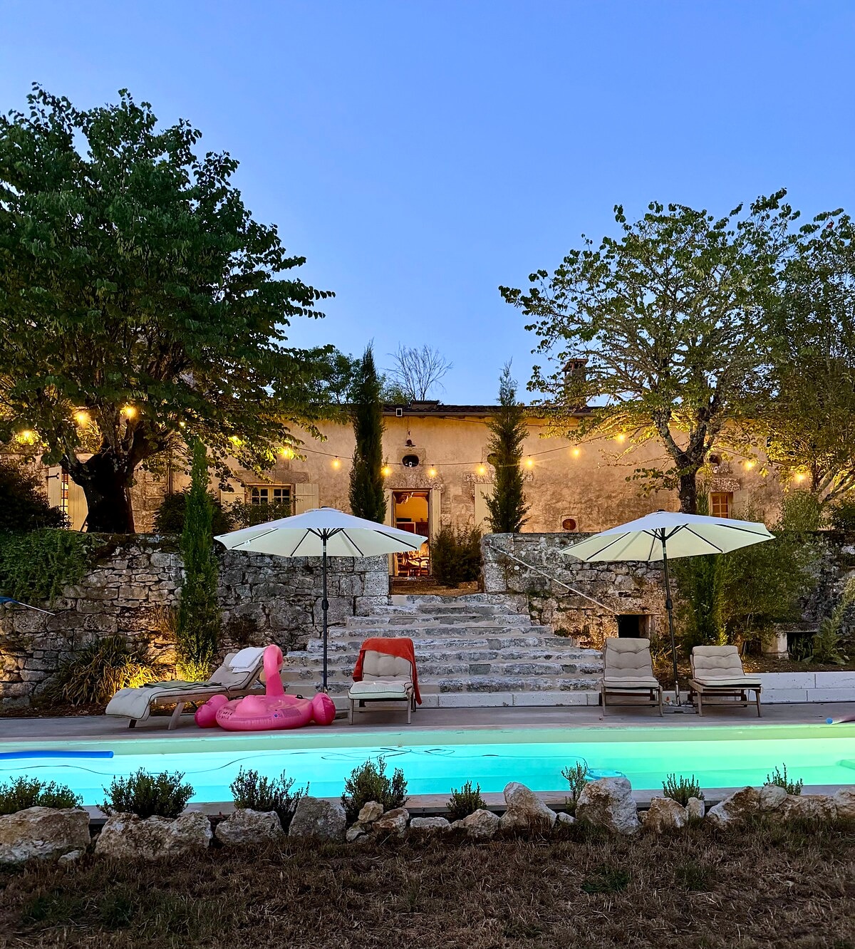 The illuminated pool and stone terrace at dusk