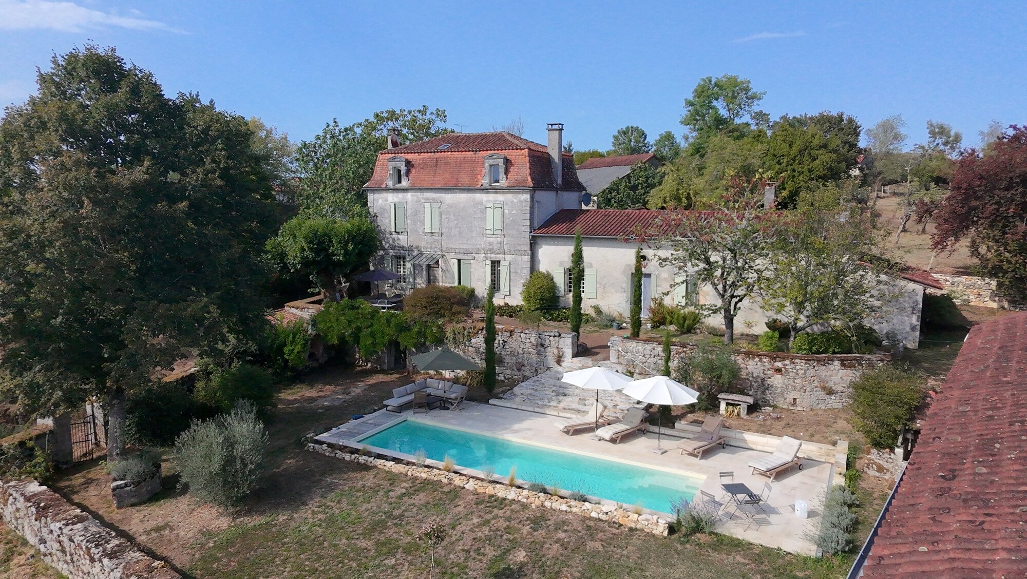 Elevated view across the pool terrace towards the historic farmhouse