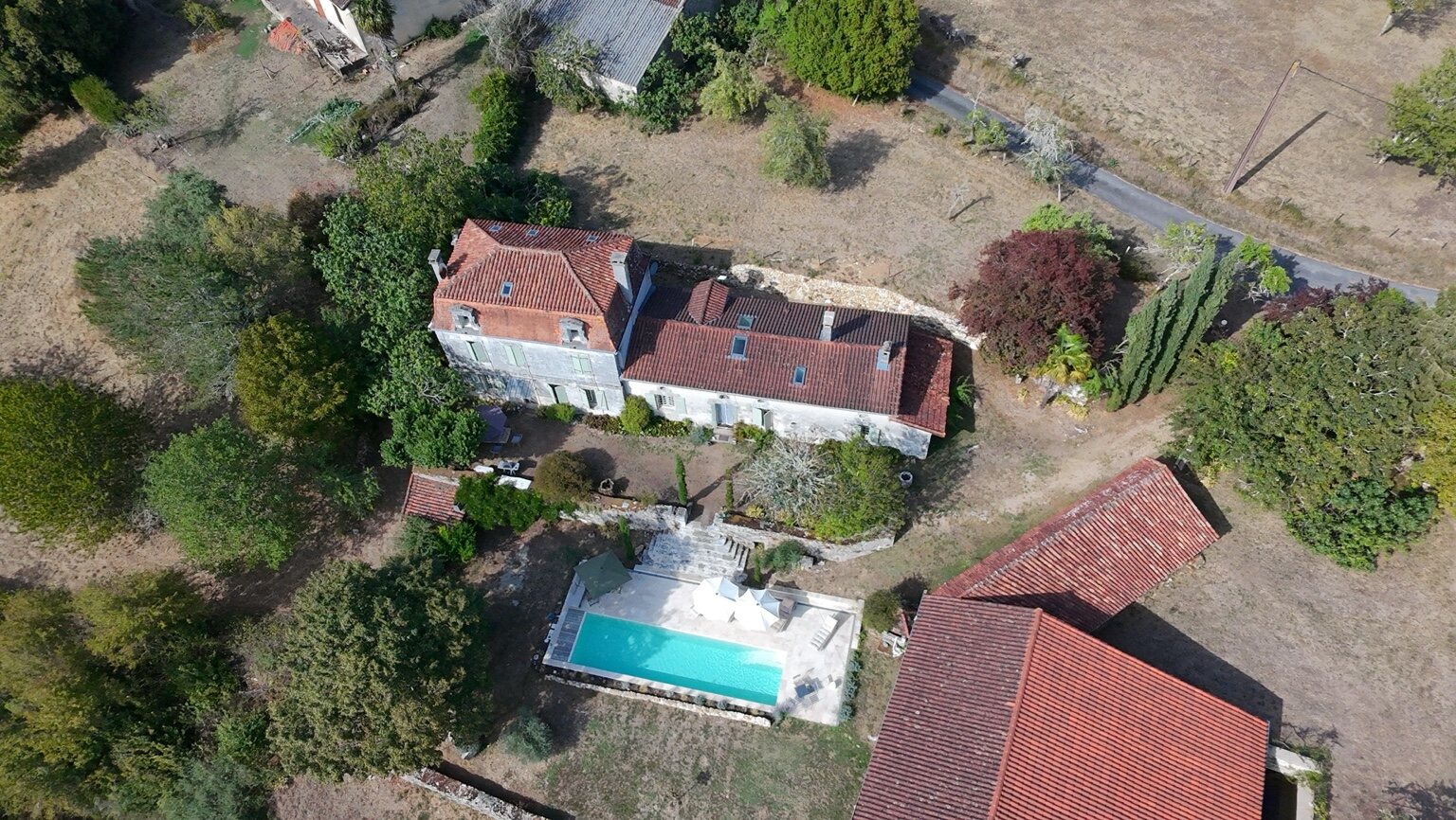 Aerial view of Maison Rivers showing the farmhouse, swimming pool, barn and surrounding grounds